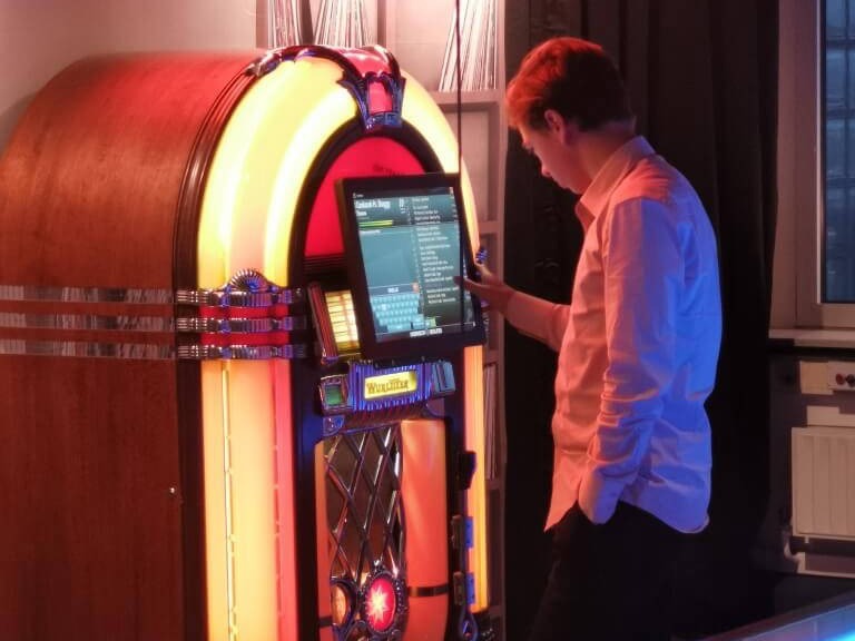 jonge man die voor de wurlitzer jukebox staat en een liedje zoekt